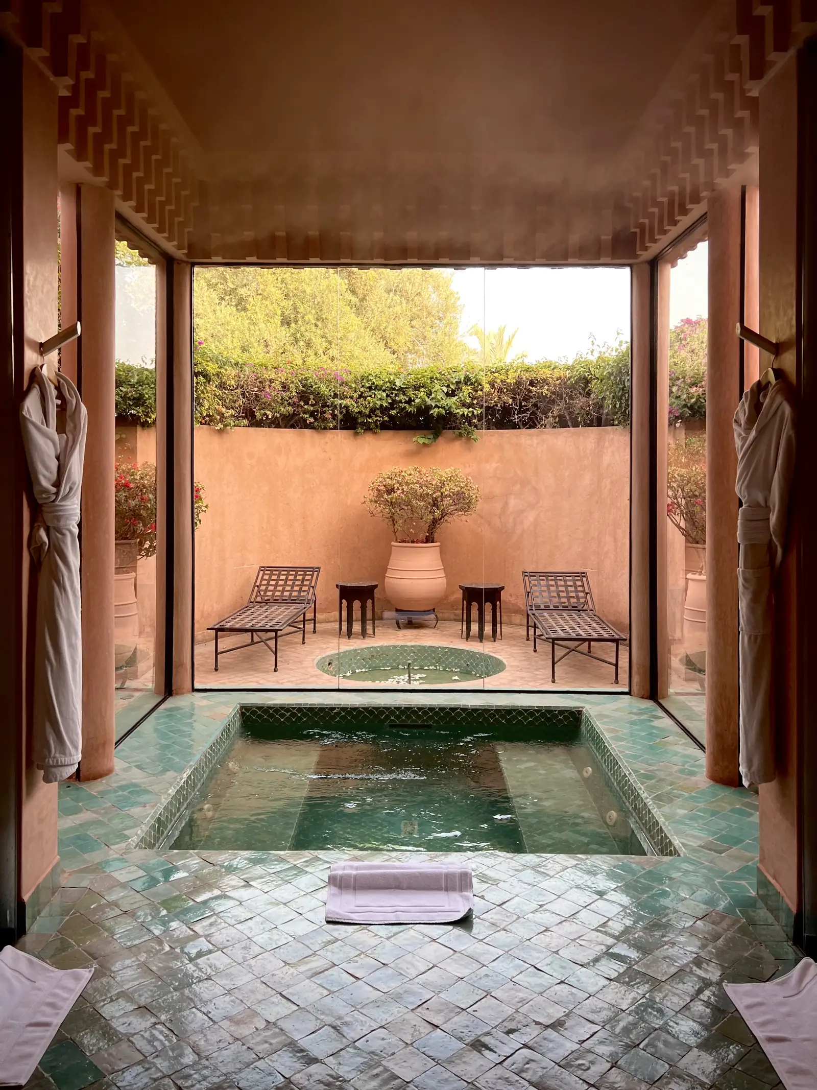 A tiled courtyard pool framed by terracotta walls and greenery.