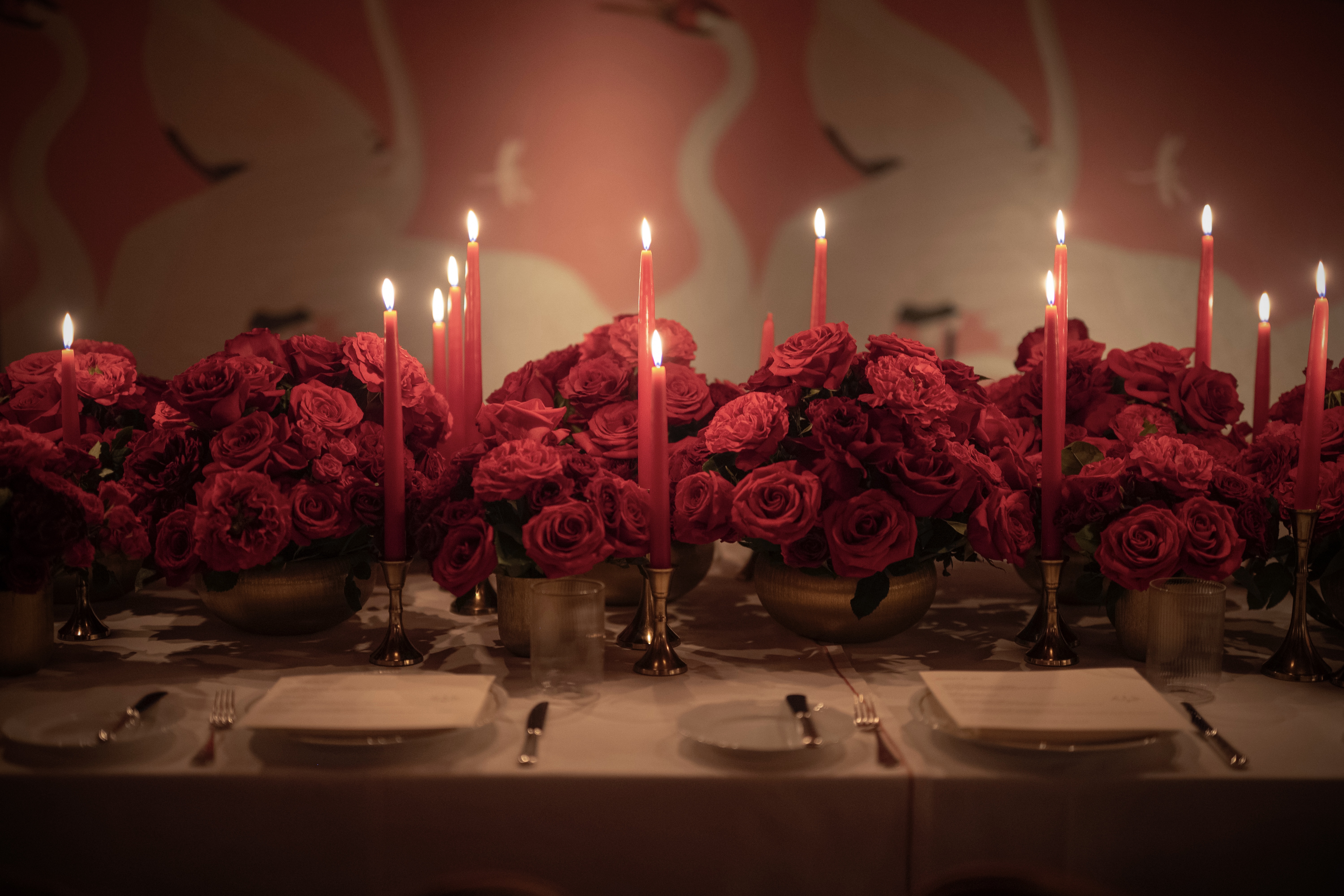 A candlelit table set with red roses.